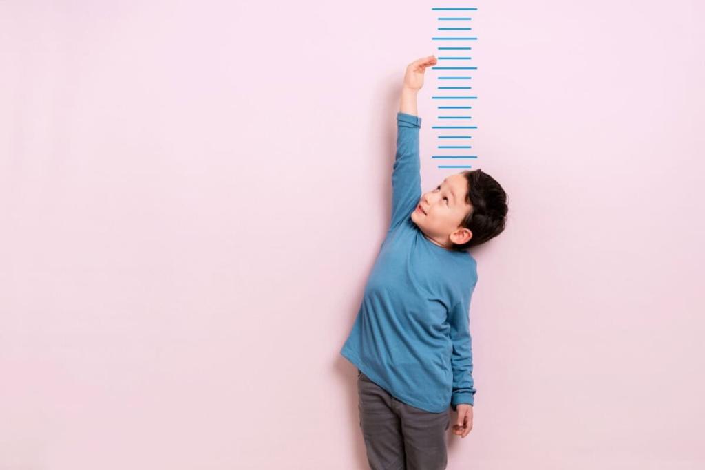 Child measures his height on wall. He is growing taller.