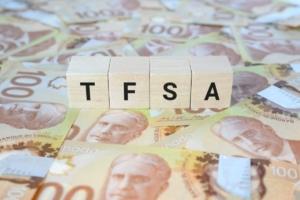 TFSA (Tax-Free Savings Account) on wooden blocks and Canadian one hundred dollar bills.
