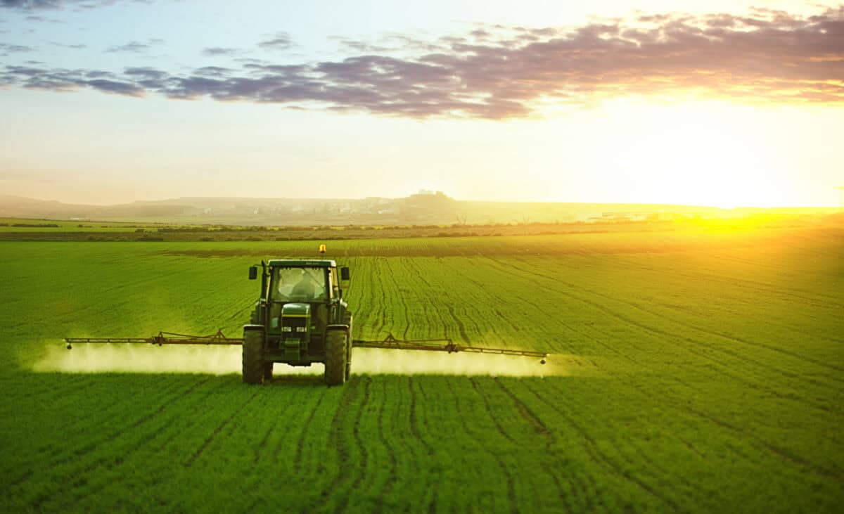 Tractor spraying a field of wheat with fertilizer