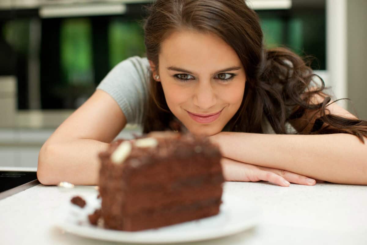 woman stares at chocolate layer cake